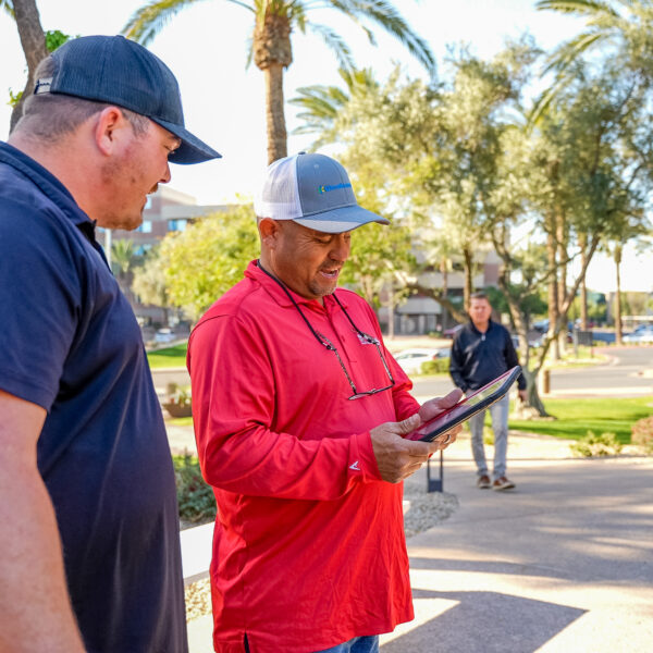 Two irrigation experts on a property looking at a tablet