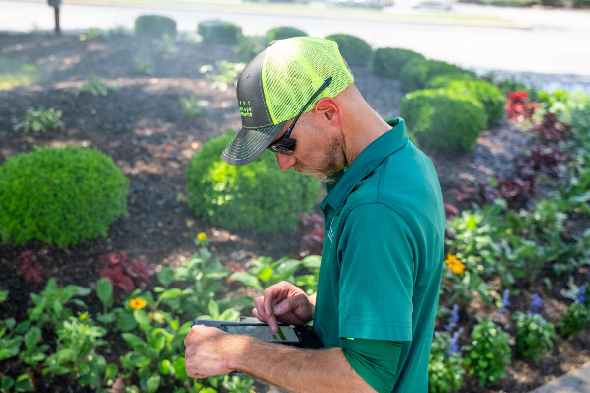 Irrigation specialist working on iPad next to beautiful landscape