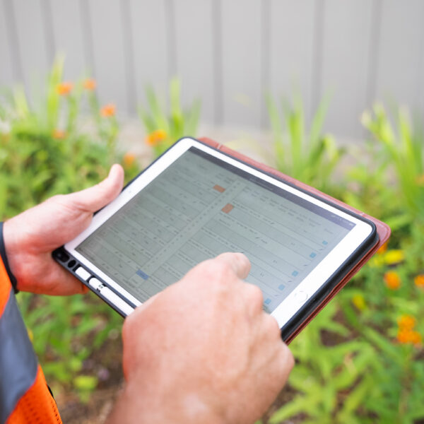 Tablet in a technician's hands controlling sprinklers for the landscape