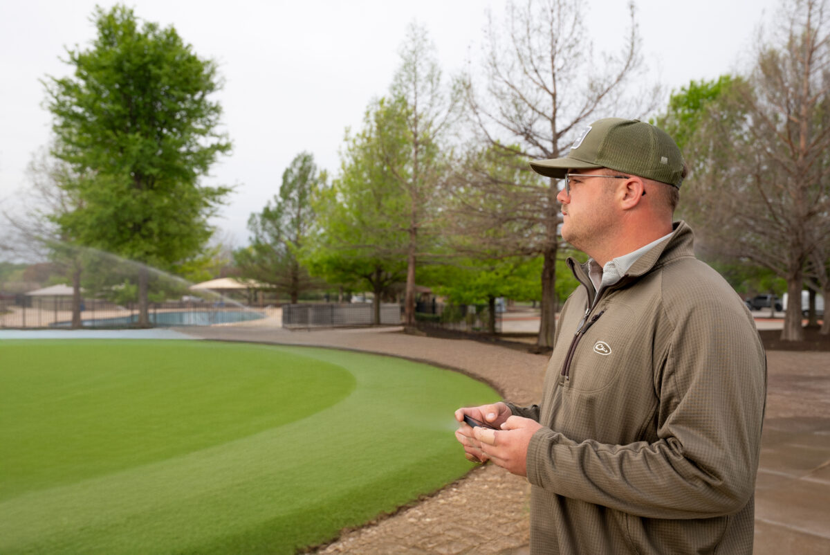 Technician controlling sprinklers on a property via his iPhone